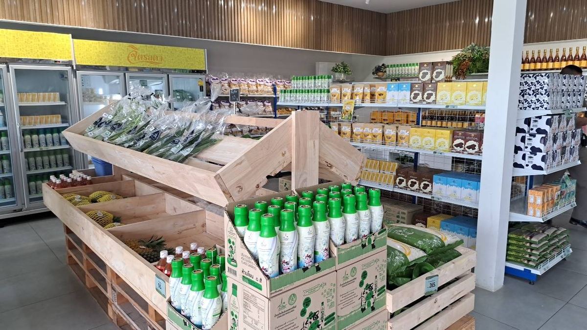 ภายในร้านจำหน่ายผลิตภัณฑ์โครงการชั่งหัวมัน มีลังไม้วางผักและขวดผลิตภัณฑ์ ตู้แช่ และชั้นวางสินค้า