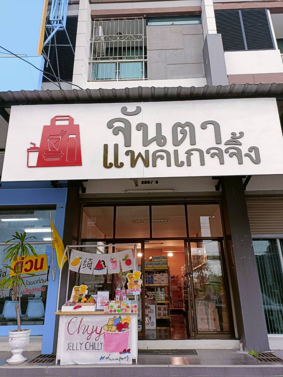 หน้าร้านจันตา แพคเกจจิ้ง ป้ายสีขาวมีโลโก้ถุงสีแดง เหนือประตูกระจกของอาคารพาณิชย์