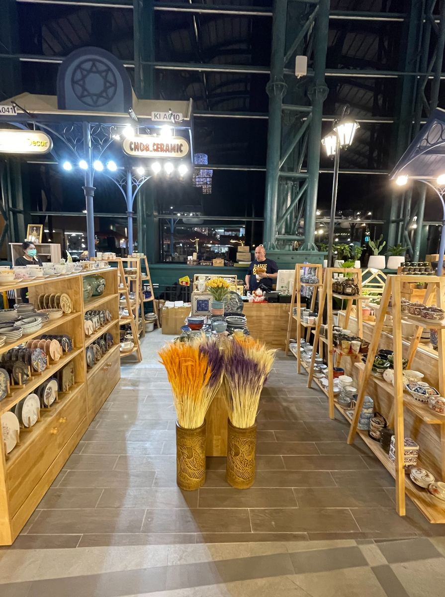 ร้าน CHOBCERAMIC มีจานชามเซรามิกบนชั้นไม้สองฝั่งและป้ายชื่อร้านแขวนด้านบน