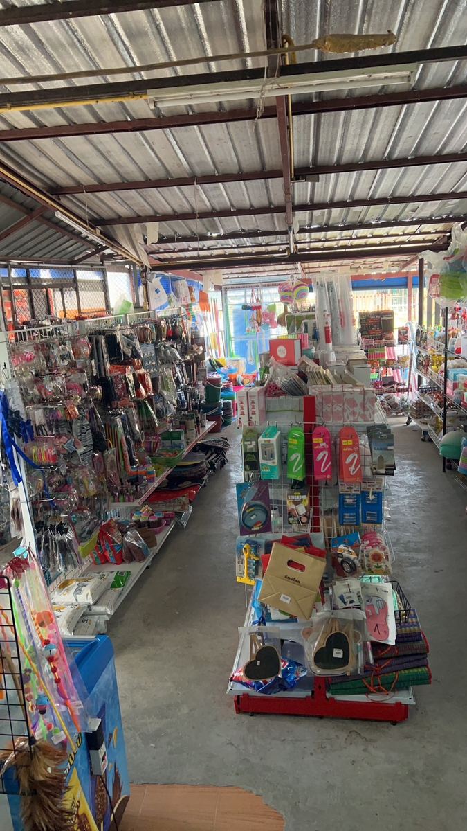 ภายในร้านดีจัง20 หลังคาเหล็ก มีแผงแขวนของใช้ สายชาร์จ และชั้นสินค้าหลายแถว