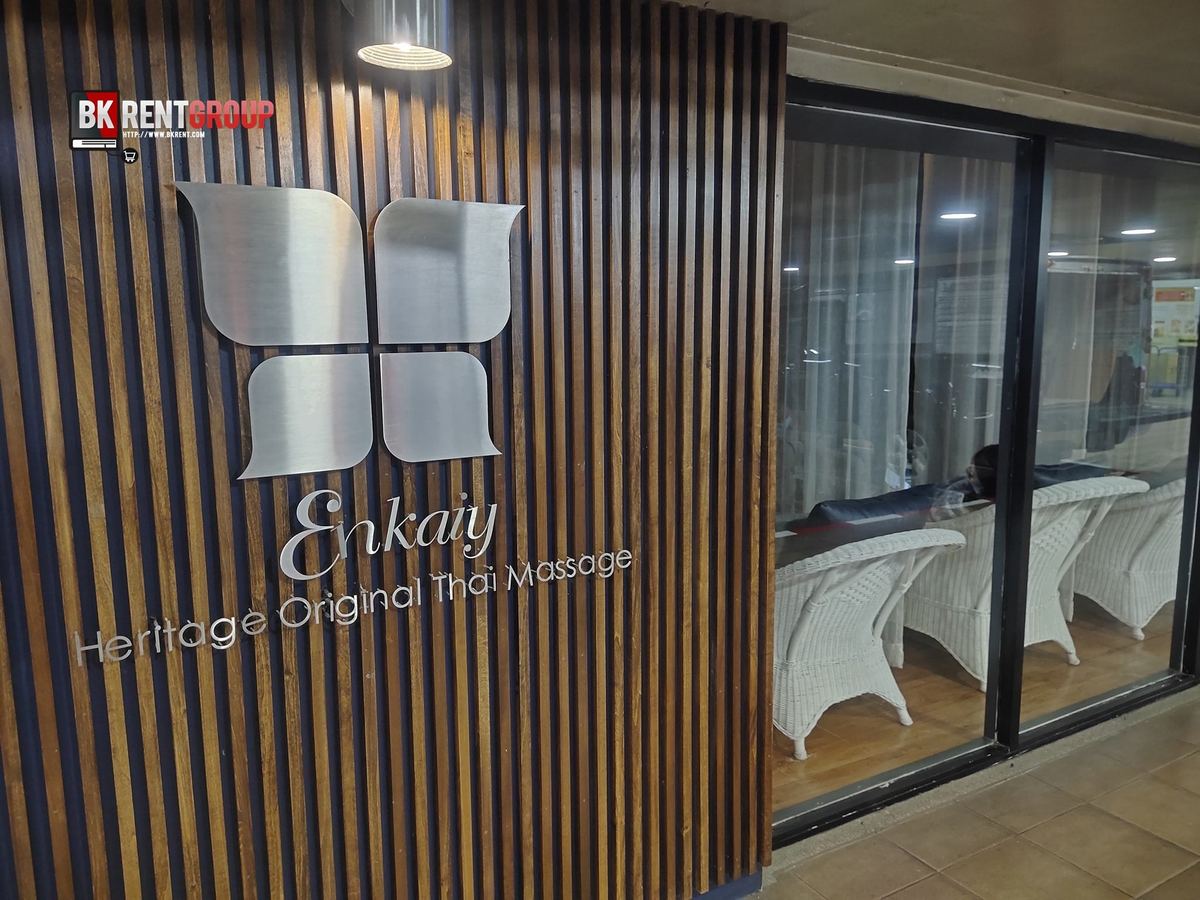 หน้าร้าน Enkaiy Heritage Original Thai Massage มีโลโก้สแตนเลสบนผนังไม้ระแนงข้างประตูกระจก