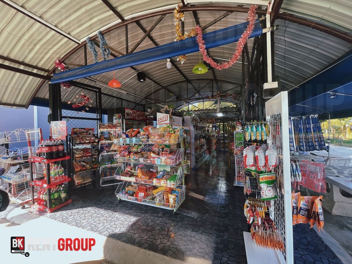 หน้าร้านค้ายาย ร้านเปิดโล่งใต้หลังคาโค้ง มีชั้นขนมและเครื่องดื่ม ประดับสายรุ้ง