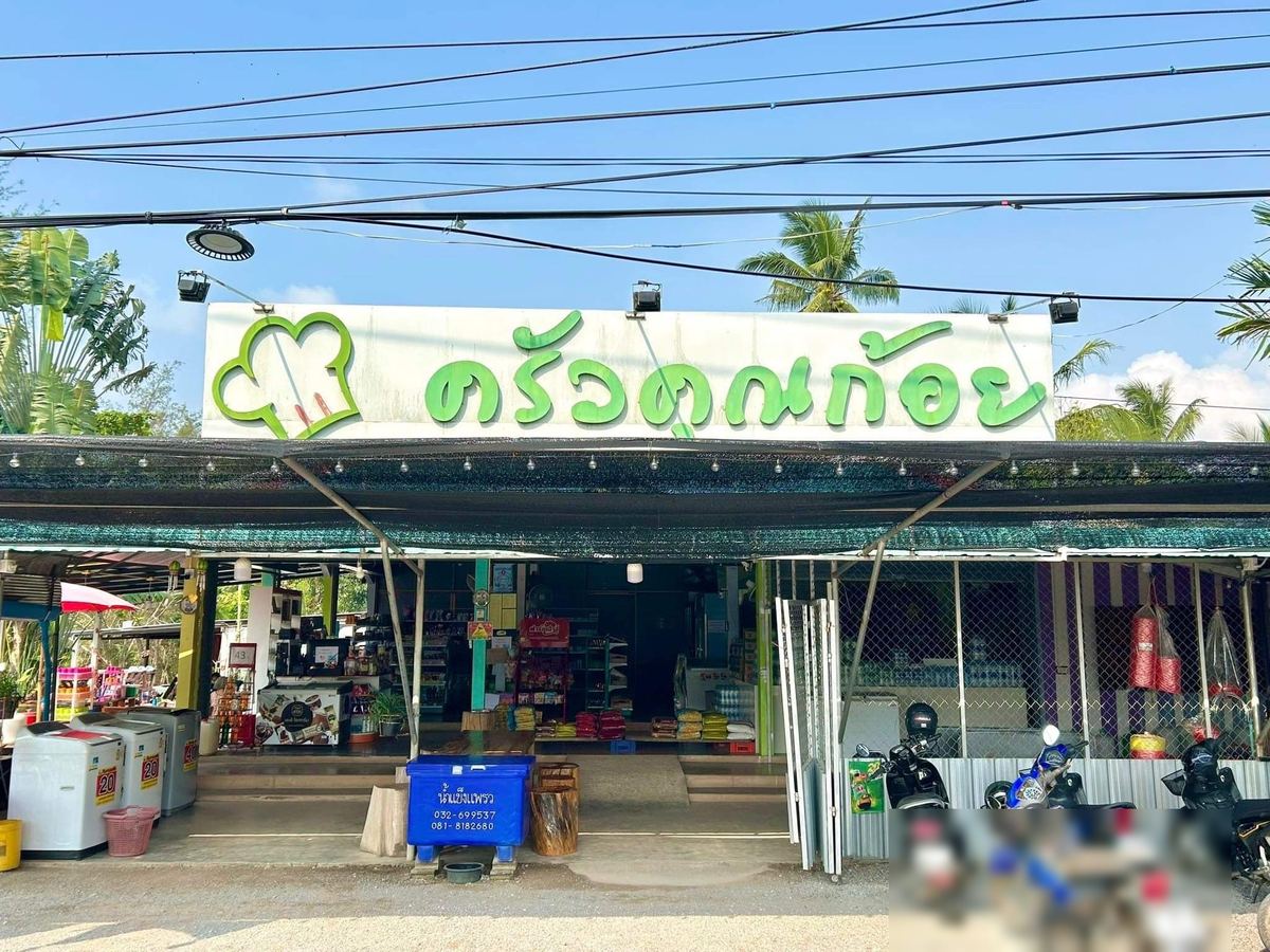 หน้าร้านครัวคุณก้อย ป้ายตัวอักษรสีเขียวพร้อมโลโก้หมวกเชฟ มีรถจักรยานยนต์จอดหน้าร้าน