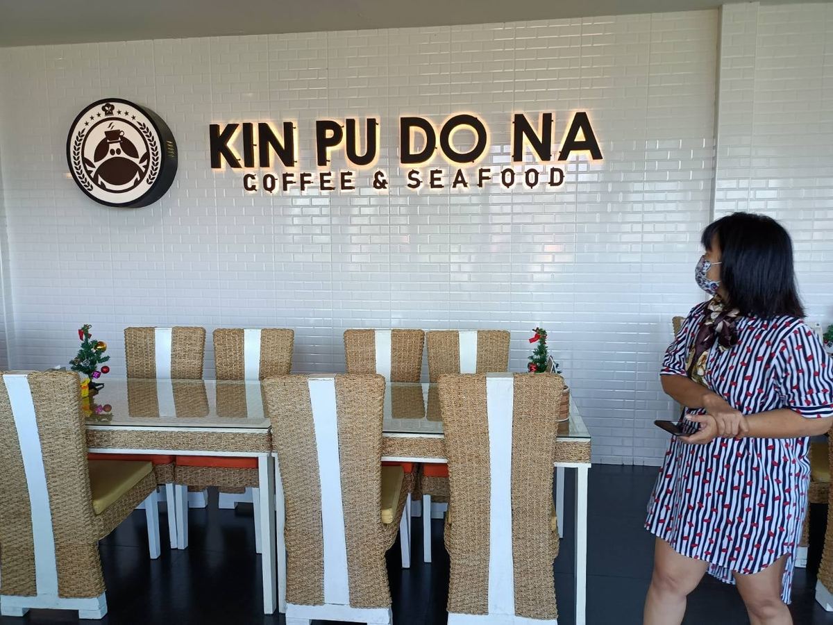 ป้ายชื่อร้าน KIN PU DO NA บนผนังอิฐสีขาว