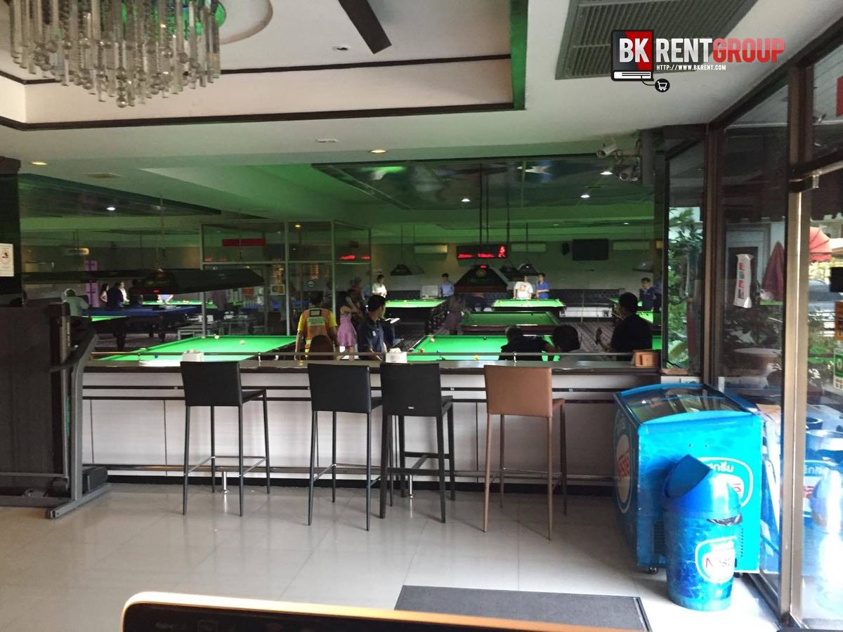มุมบาร์ของ Max-B Snooker House มีเก้าอี้สูงและโต๊ะสนุกเกอร์เปิดไฟสีเขียวหลังกระจก
