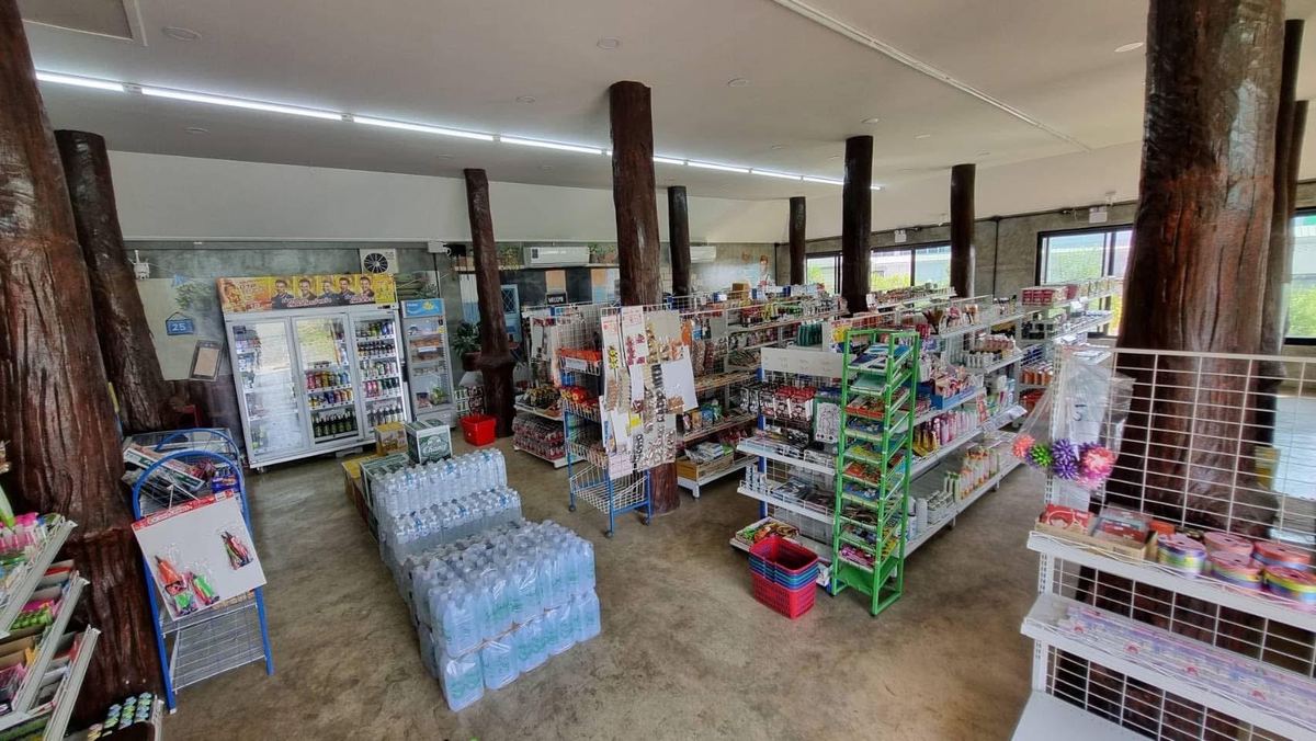 ภายในร้านมินิมาร์ทในกรุงเทพฯ มีเสาไม้ต้นใหญ่ ตู้แช่เครื่องดื่ม และชั้นสินค้าหลายแถว