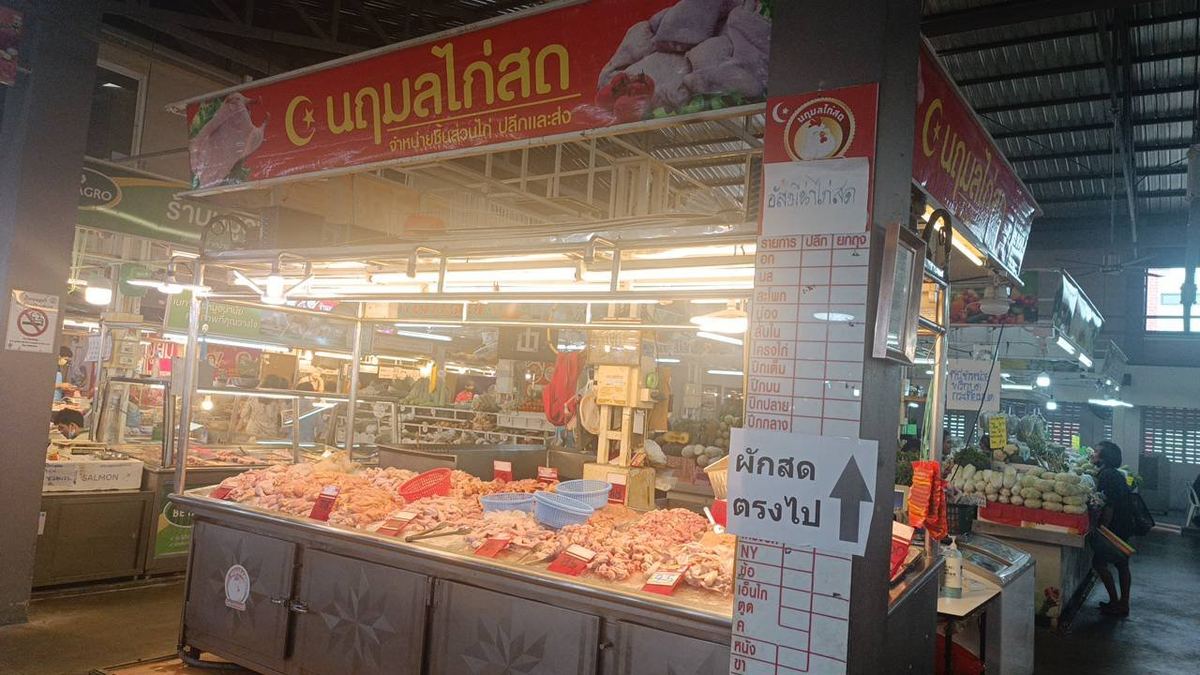 แผงนฤมลไก่สดในตลาด ป้ายสีแดงชื่อร้าน ชิ้นส่วนไก่วางบนแผงสแตนเลส