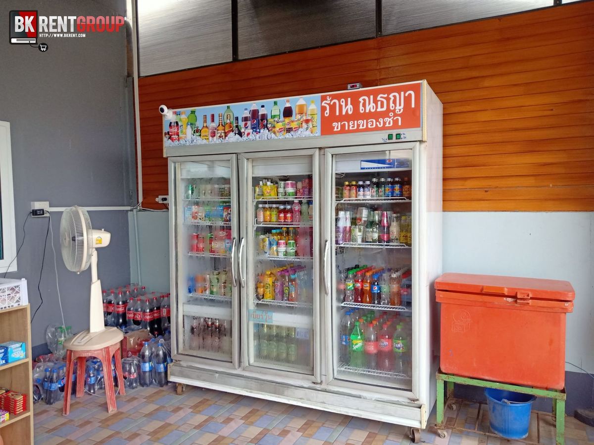 ตู้แช่เครื่องดื่มสามประตูของร้านณธญา ขายของชำ มีป้ายชื่อร้านสีส้มด้านบน