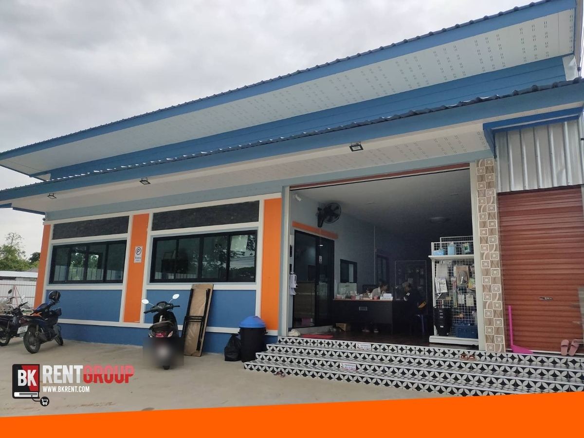 หน้าร้านนพศร วัสดุก่อสร้าง อาคารชั้นเดียวสีฟ้าสลับส้ม ประตูร้านเปิดกว้าง และบันไดปูกระเบื้องลาย