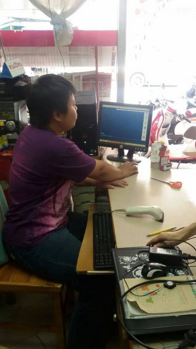 พนักงานนั่งที่คอมพิวเตอร์ ข้างเครื่องสแกนบาร์โค้ด