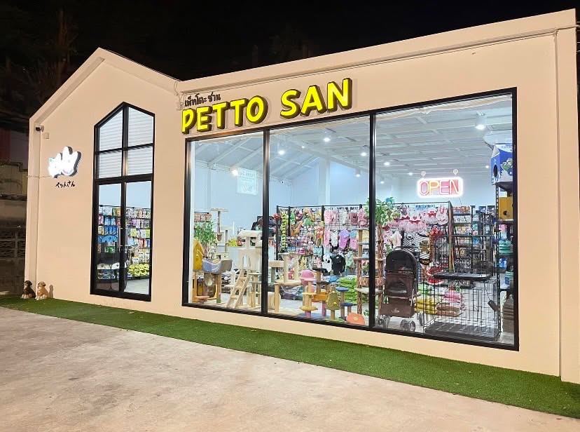 หน้าร้าน PETTO SAN ยามค่ำ ป้ายชื่อสีเหลือง มองผ่านกระจกเห็นคอนโดแมวและชั้นสินค้าสัตว์เลี้ยง