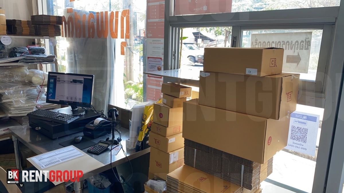 จุดขายของโรงงานถุงพลาสติก จอโปรแกรม ลิ้นชักเก็บเงิน และเครื่องพิมพ์ใบเสร็จ ข้างกองกล่องพัสดุ