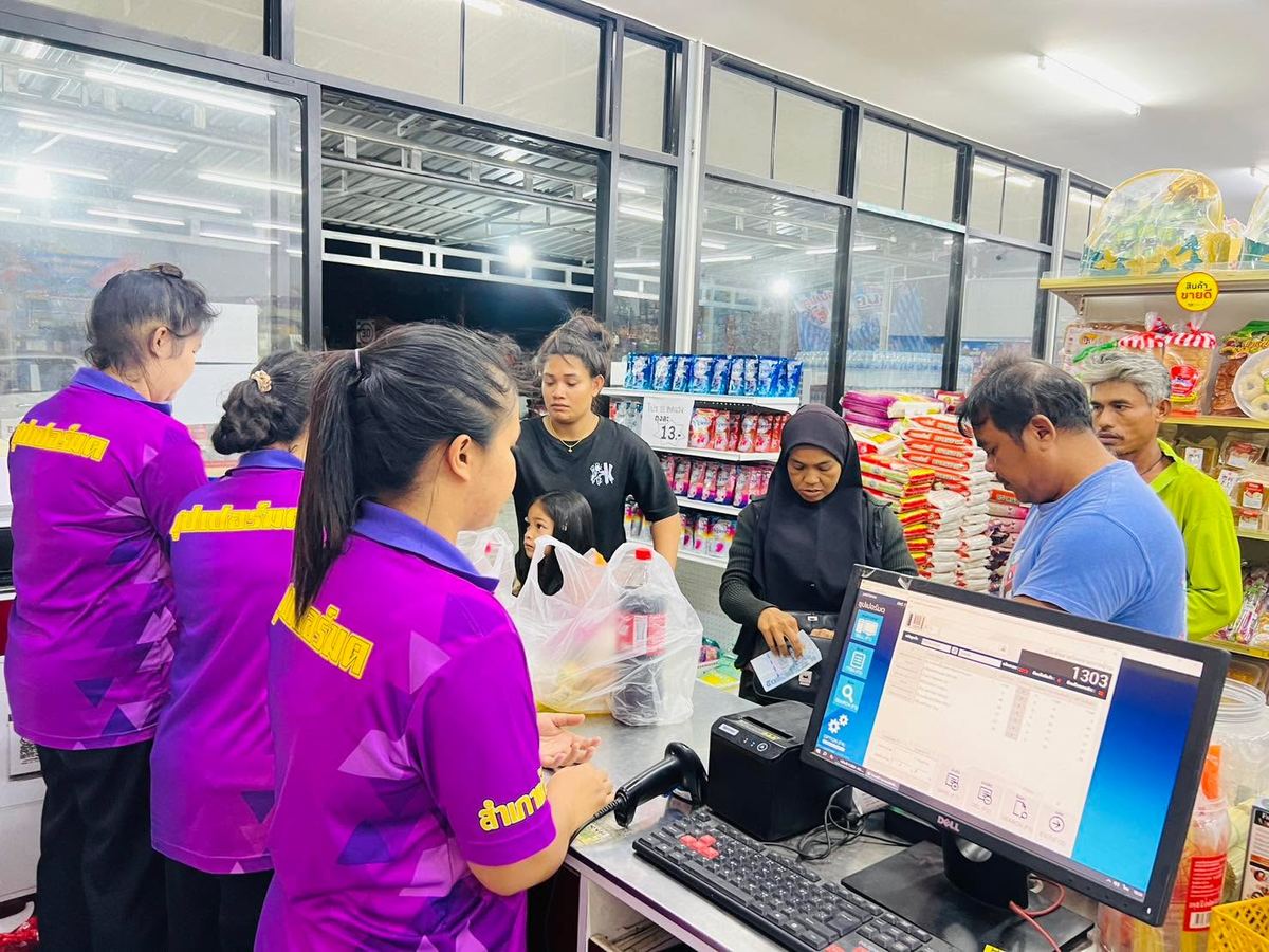 เคาน์เตอร์คิดเงินร้านซุปเปอร์มด พนักงานใส่เสื้อสีม่วงสกรีนชื่อร้าน ลูกค้ายืนรอหน้าจอขาย