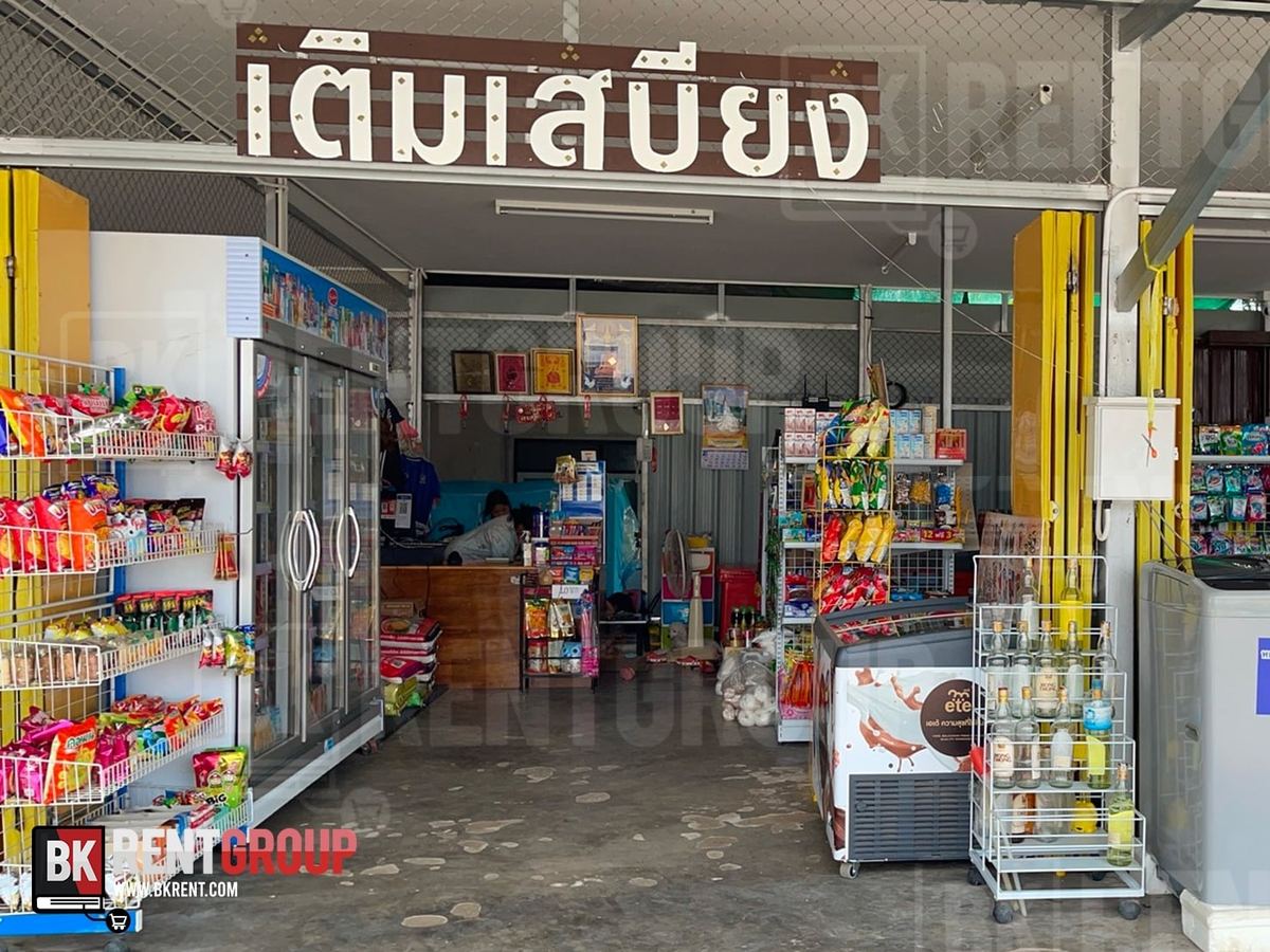 หน้าร้านเติมเสบียง ป้ายไม้สีน้ำตาลตัวอักษรสีขาว ตู้แช่เครื่องดื่ม ชั้นขนม และตู้ไอศกรีมหน้าร้าน