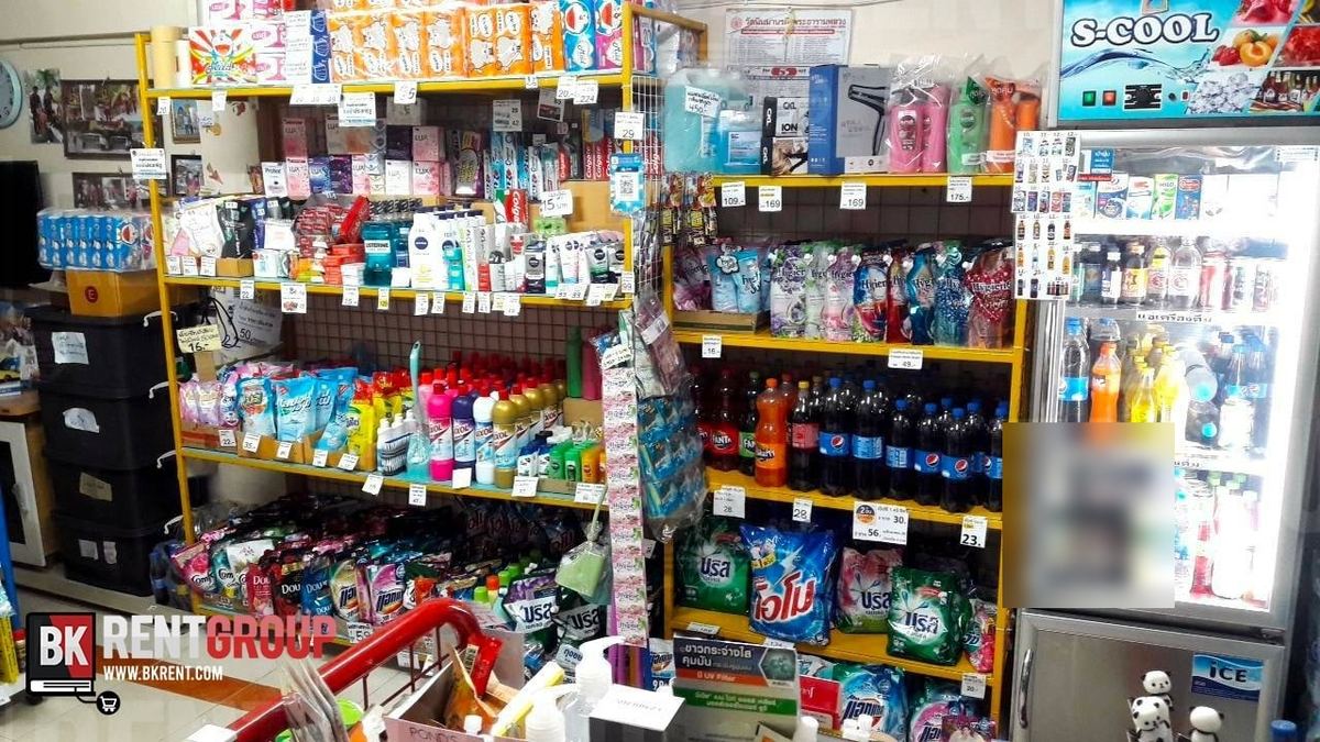ภายในร้านวีเพย์ส (V-PAYS) ชั้นเหล็กสีเหลืองวางของใช้และน้ำอัดลม ข้างตู้แช่กระจกใส่เครื่องดื่ม