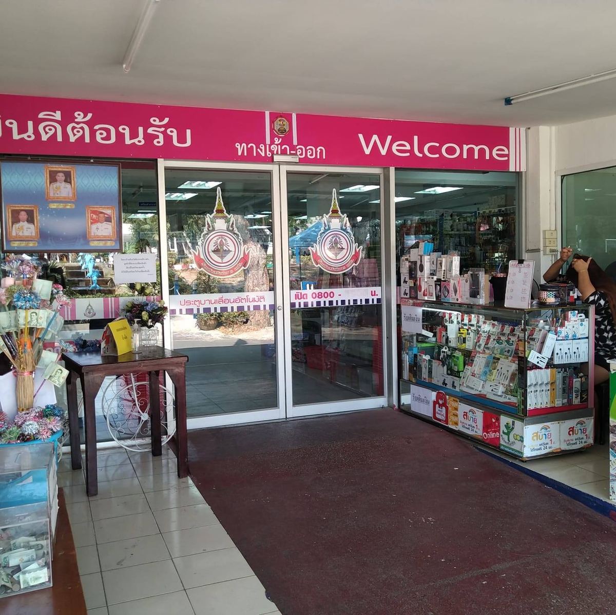 ทางเข้าร้านค้าสวัสดิการ กองการฝึก กองเรือยุทธการ มีป้ายยินดีต้อนรับสีชมพูเหนือประตูกระจก